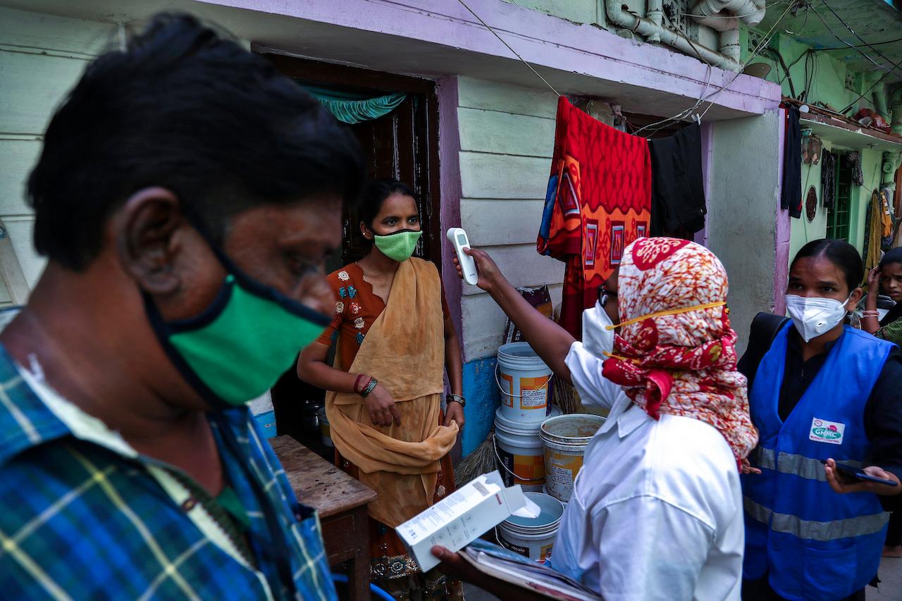 An Indian health worker checks the body temperature of a woman during a door-to-door survey conducted as a precaution against Covid-19 in Hyderabad, India, May 6. Photo: AP