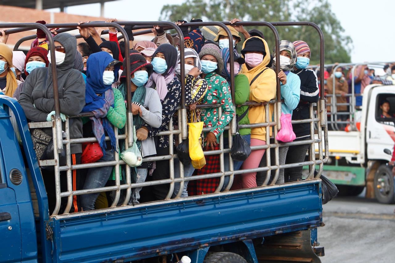 Garment workers stand on the trucks as they head to work outside Phnom Penh, Cambodia, May 6. Cambodia on Thursday ended a lockdown in the capital region. Photo: AP