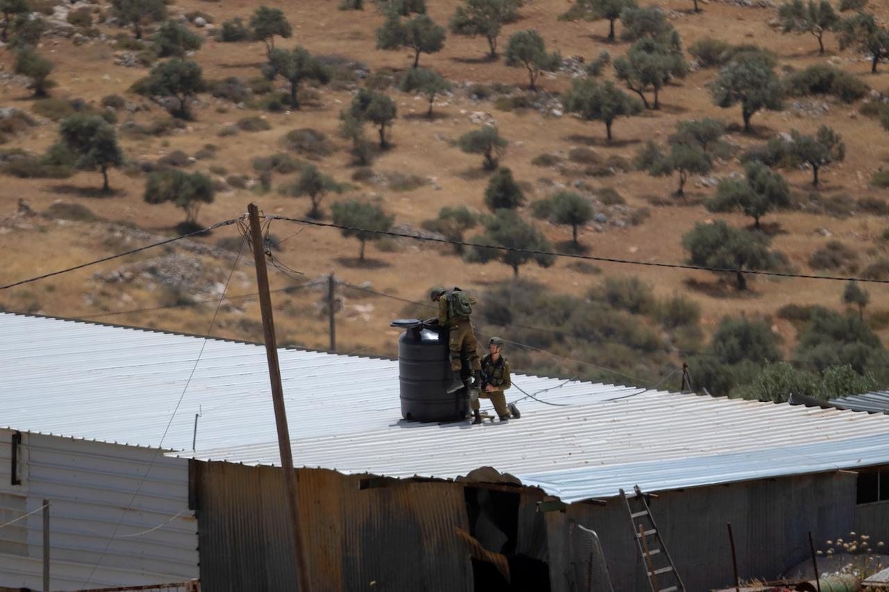 Israeli soldiers search for a suspected Palestinian gunman in the village of Aqraba, near the West Bank town of Nablus, May 5. On Sunday gunmen in a passing car opened fire at Israelis standing at a major intersection in the Israeli-occupied West Bank, injuring three of them, according to rescue officials and the military. Photo: AP