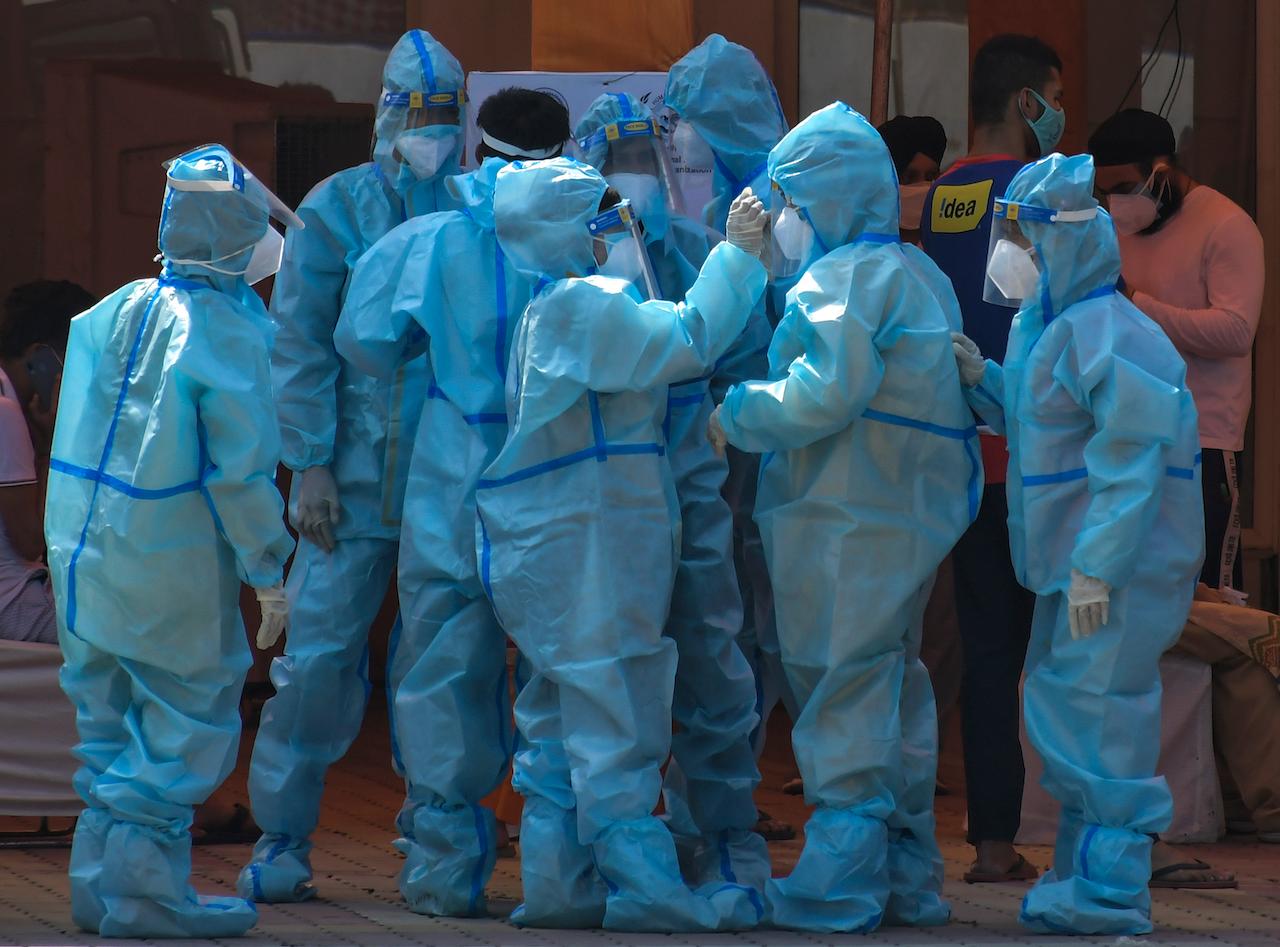 Health workers and volunteers in personal protective suits wait to receive patients outside a Covid-19 hospital in New Delhi, India, May 10. Photo: AP