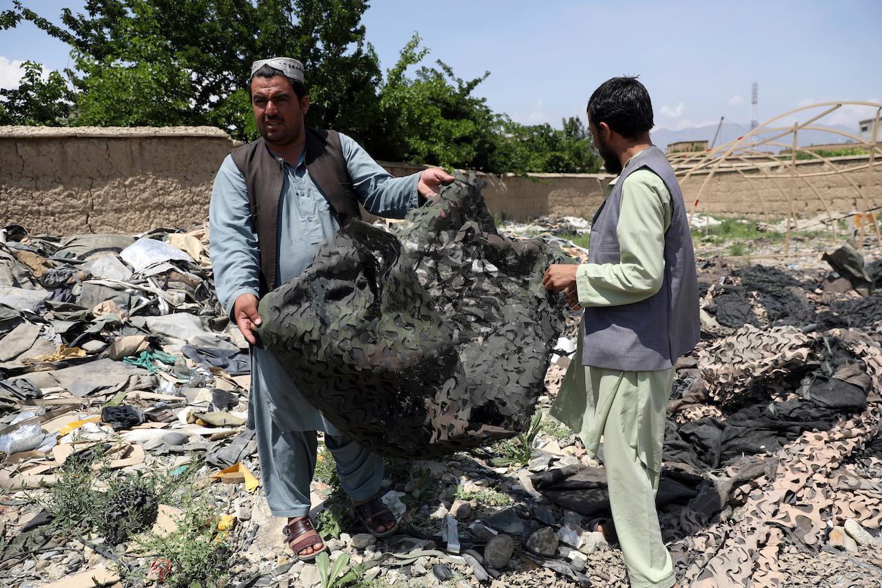 Afghan men hold scraps of tenting at a scrapyard outside Bagram Air Base, northwest of the capital Kabul, Afghanistan, May 3. Photo: AP