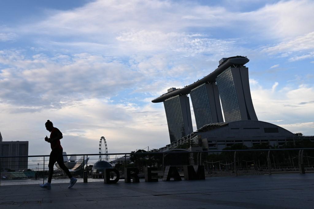 A man jogs along the Marina Bay promenade in Singapore, May 7. Health regulations in the city-state allow individuals to remove their mask when engaging in strenuous exercise although they must put the mask back on once this is completed. Photo: AFP