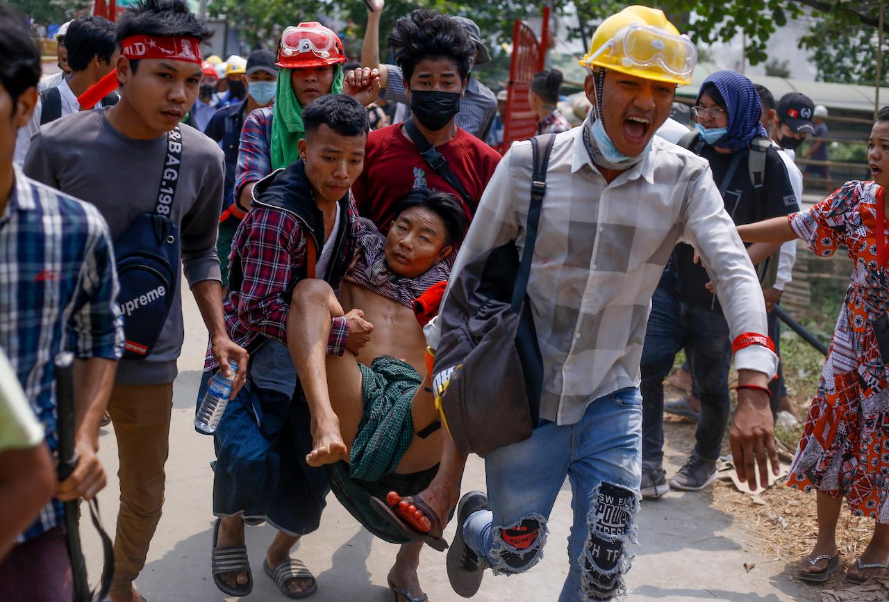 Anti-coup protesters carry an injured man following clashes with security in Yangon, Myanmar, March 14. Photo: AP