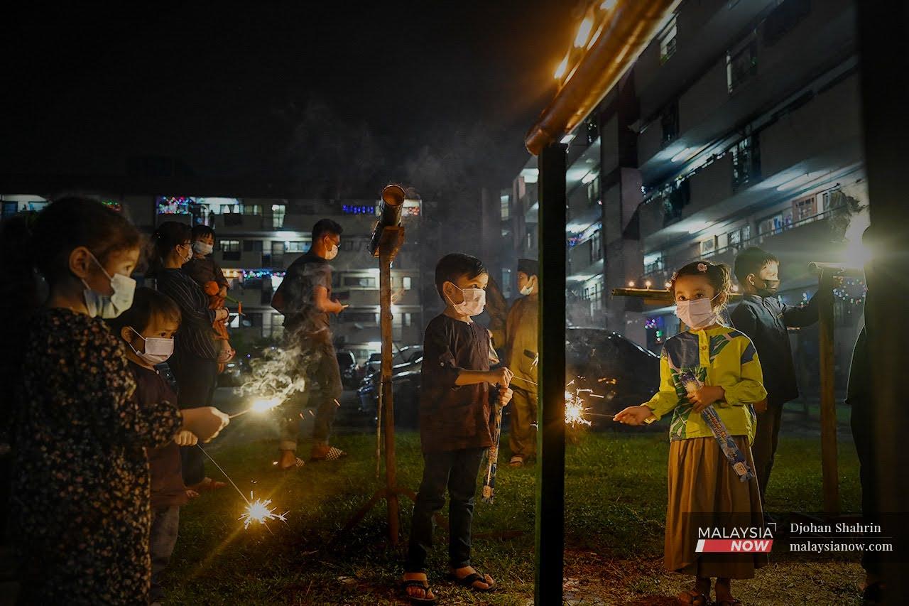 Children play with sparklers at the Sri Melaka flats in Cheras, Kuala Lumpur, ahead of Hari Raya this week. Hari Raya visits are not allowed under the movement control order which came into effect across the country today.