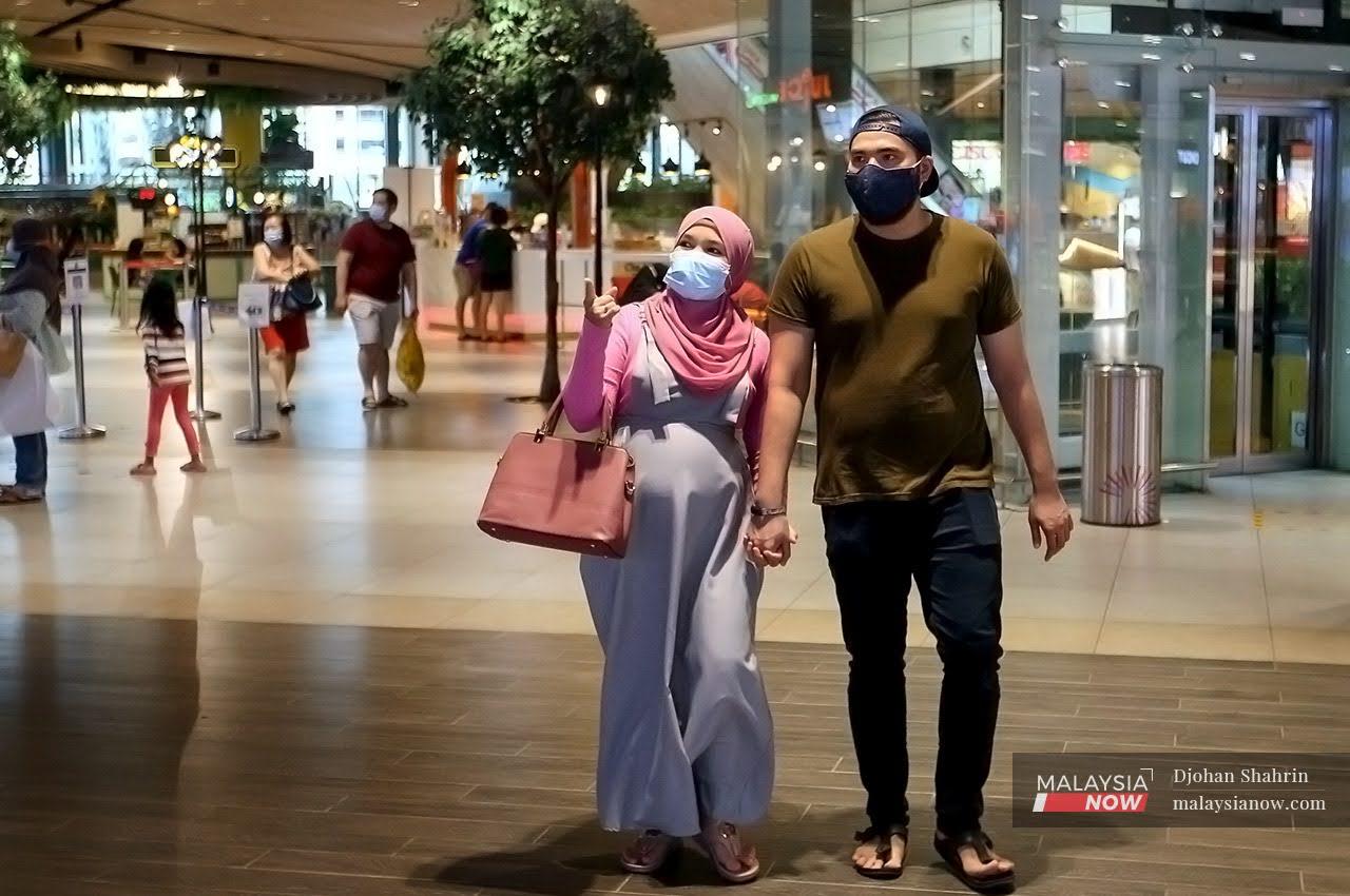 Sepasang suami isteri berjalan berpimpin tangan di sebuah kompleks membeli belah di Shah Alam. PKP 3.0 yang diumumkan kerajaan tidak menutup sektor ekonomi seperti kali pertama sekatan itu diperkenalkan.