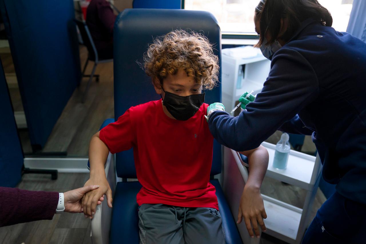 Seorang kanak-kanak berusia 12 tahun di Tustin, California, memegang tangan ibunya ketika menerima vaksin Pfizer Covid-19 daripada seorang pekerja kesihatan pada 13 Mei, 2022. Gambar: AP