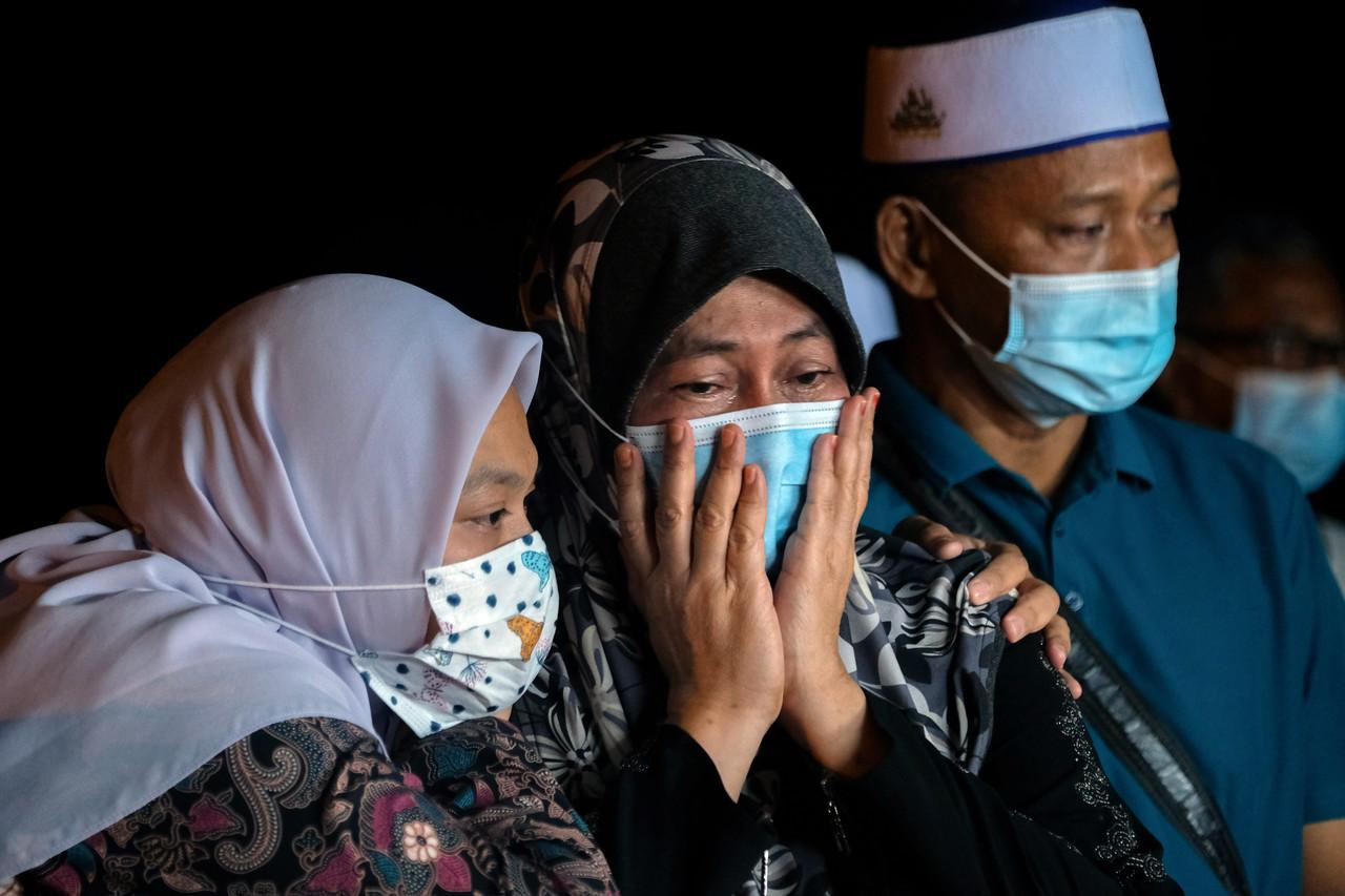Haziq Kamaruddin's mother, Rulifah Salehin (centre), is comforted by his widow Shahira Abdul Halim (left) at his burial at the Taman Koperasi Serkam Darat cemetery in Merlimau, Jasin, early this morning.