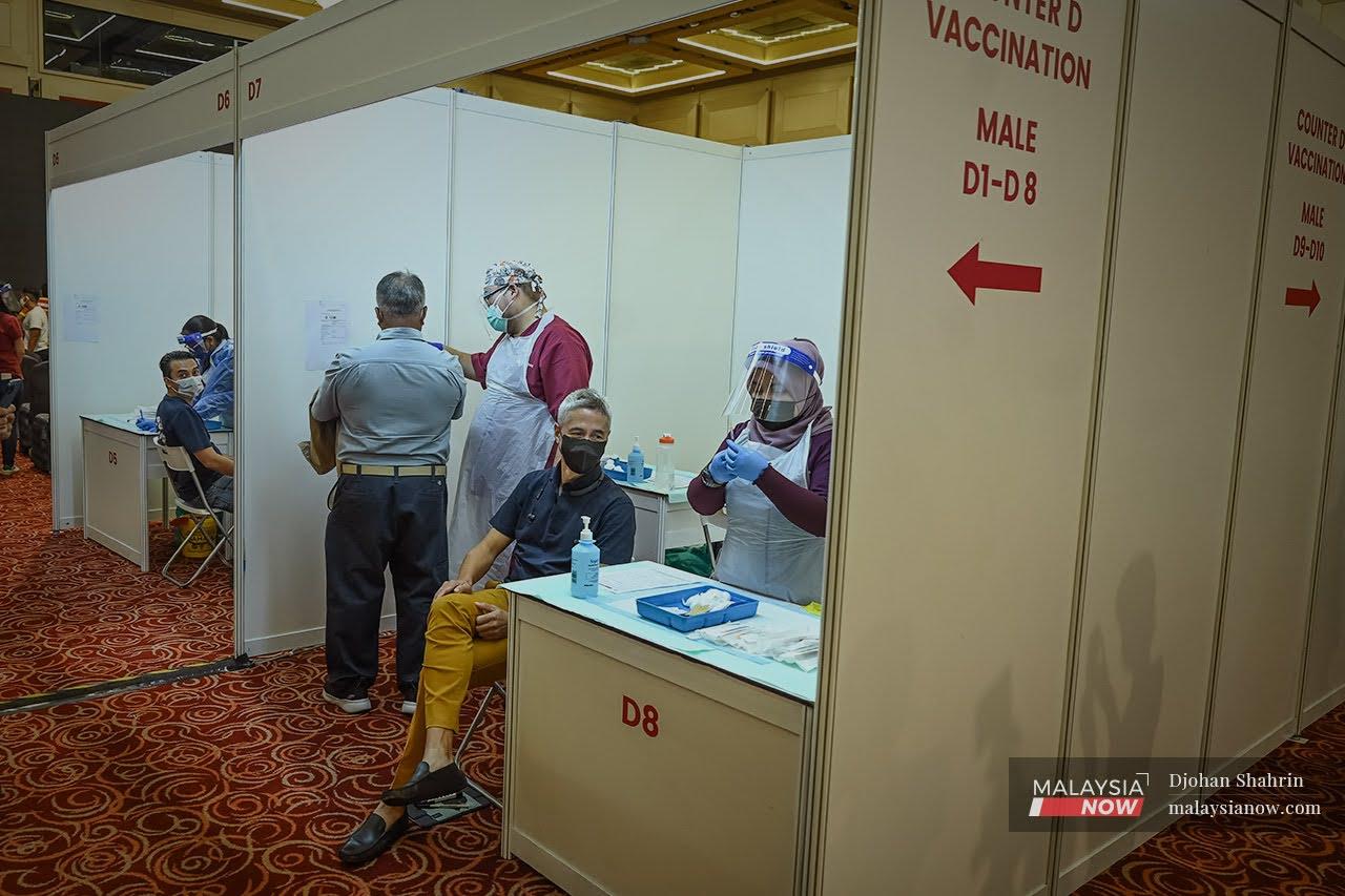 Pegawai perubatan membuat persiapan sebelum memberi suntikan vaksin AstraZeneca pada hari pertama yang dibuka pada umum kepada penduduk di Kuala Lumpur dan Selangor di Pusat Dagangan Dunia Putra.