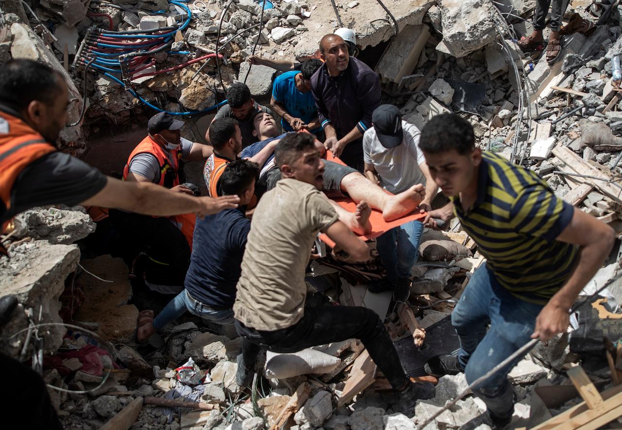 Palestinians rescue a man from under the rubble of a destroyed residential building following deadly Israeli airstrikes in Gaza City, May 16. Photo: AP