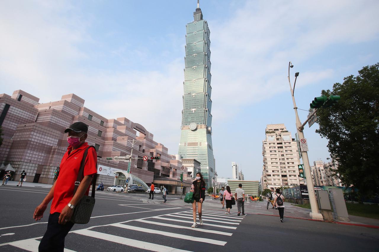 People wearing face masks to protect against the spread of the coronavirus walk past Taipei 101 building after the Covid-19 alert raise to Level 3 in Taipei, Taiwan, May 15. Photo: AP