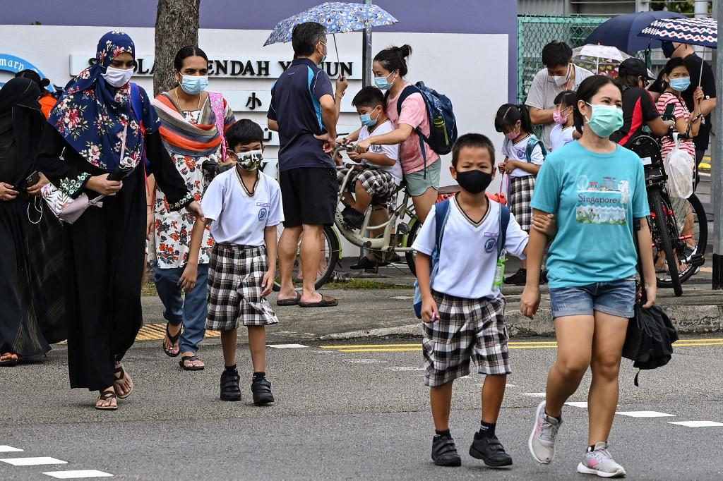 Children walk home with their guardians after school in Singapore, May 17, as the country prepares to shut all schools and switch to home-based learning until the end of the term due to a rise in the number of Covid-19 coronavirus cases. Photo: AFP