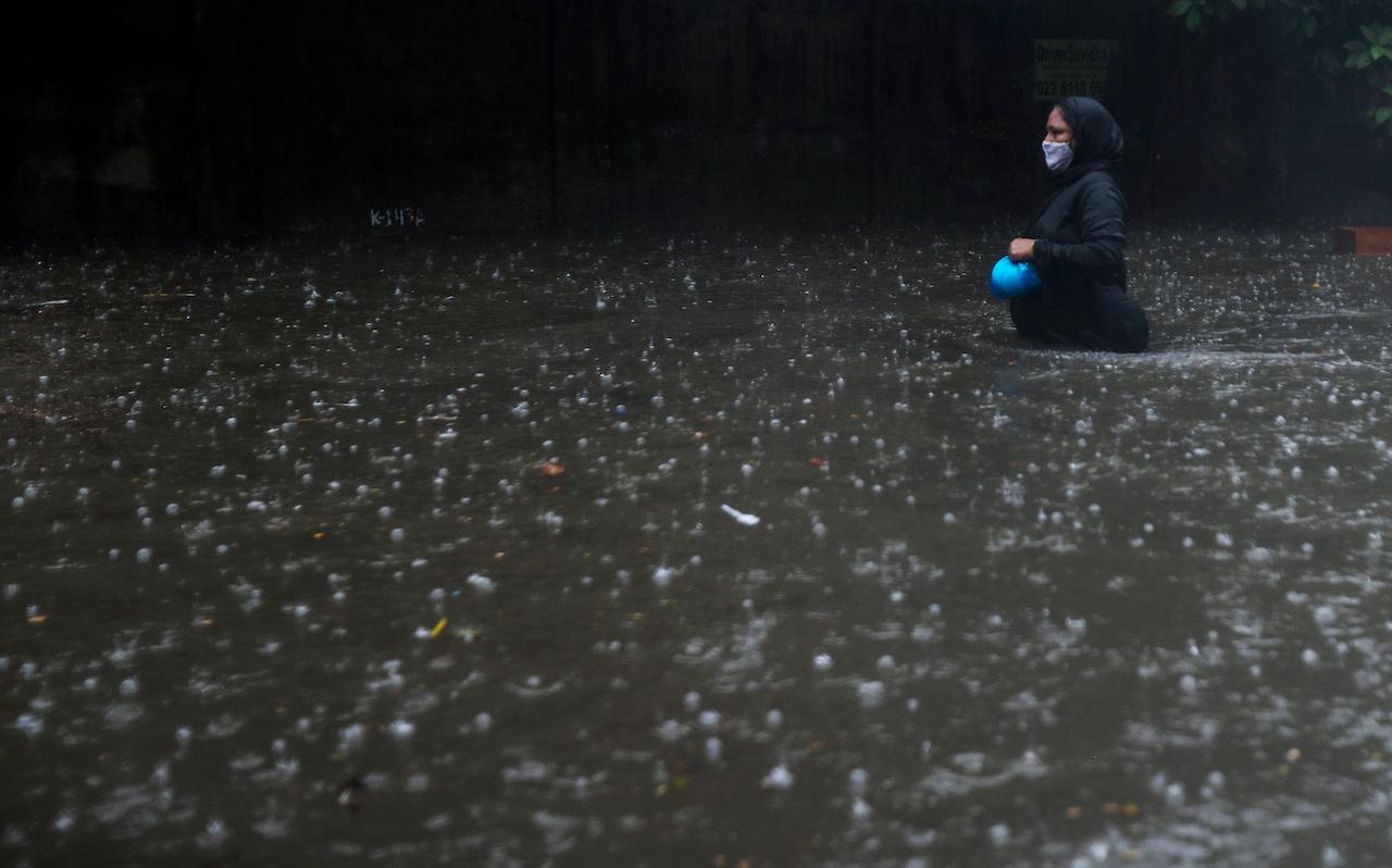 A woman wearing a mask walks through a waterlogged street in Mumbai, India, May 17. Cyclone Tauktae, roaring in the Arabian Sea, was moving toward India's western coast on Monday as authorities tried to evacuate hundreds of thousands of people and suspended Covid-19 vaccinations in one state. Photo: AP