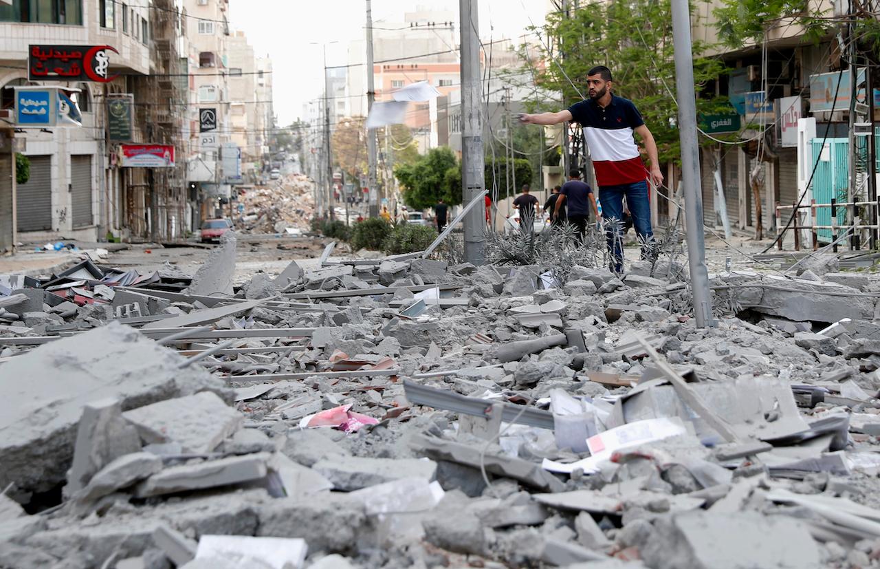 A man inspects the rubble of a destroyed commercial building and Gaza healthcare clinic following an Israeli airstrike on the upper floors of a commercial building near the health ministry in Gaza City, May 17. Photo: AP