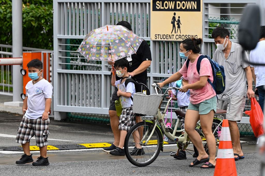 Children walk home with their guardians after school in Singapore on May 17, as the country prepares to shut all schools and switch to home-based learning until the end of the term due to a rise in the number of Covid-19 cases. Photo: AFP