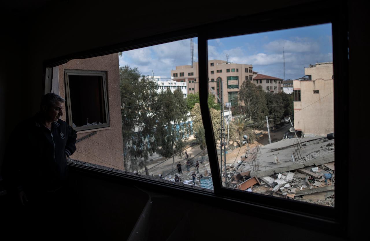 A Palestinian man looks out from a broken window at the remains of a six-story building destroyed by an early morning Israeli airstrike, in Gaza City, May 18. Photo: AP