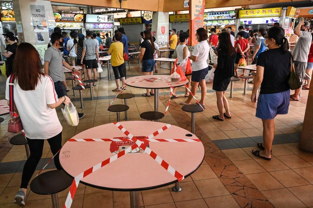 People queue to buy food as takeaway orders, as tables and chairs are cordoned off to prevent people from dining in at a hawker food centre in Singapore, May 16, the first day of increased restrictions over concerns in a rise in the number of Covid-19 cases. Photo: AFP