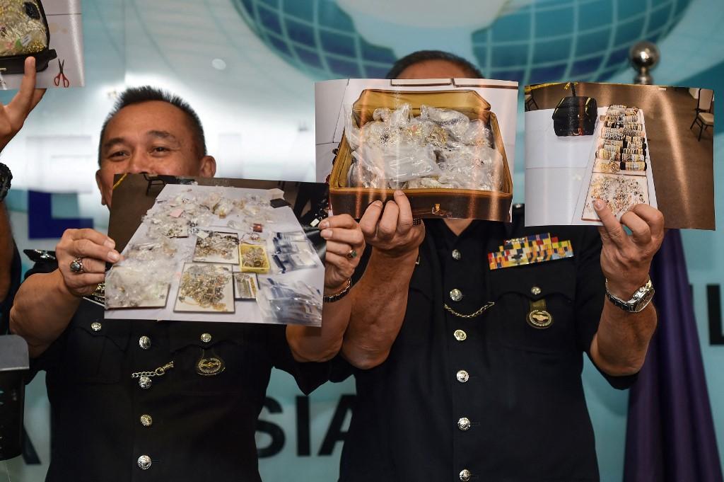 Police hold up pictures of items seized from premises linked to former prime minister Najib Razak at a press conference in Kuala Lumpur on June 27, 2018. Photo: AFP