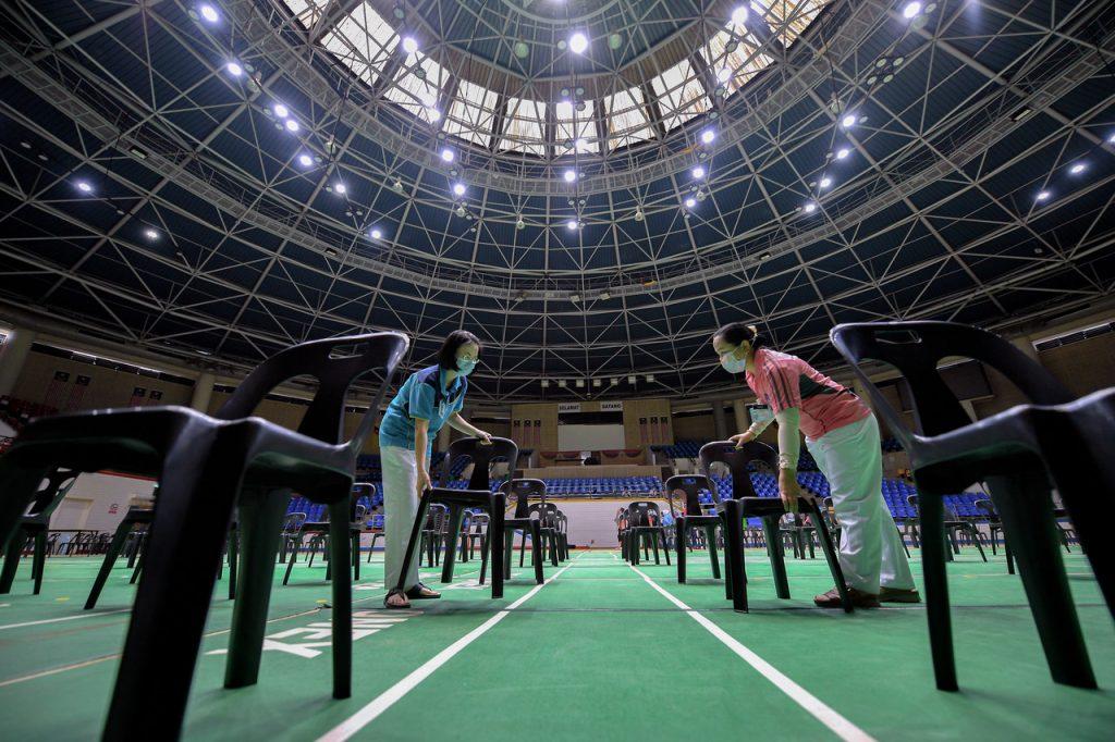 Health workers arrange chairs at the Stadium Perpaduan Covid-19 vaccination centre in Kuching. Photo: Bernama