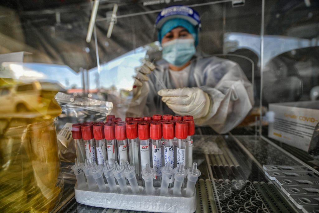 A lab technician in Kuching runs a Covid-19 test on swab samples taken from villagers in Kampung Bintawa Hulu. Photo: Bernama