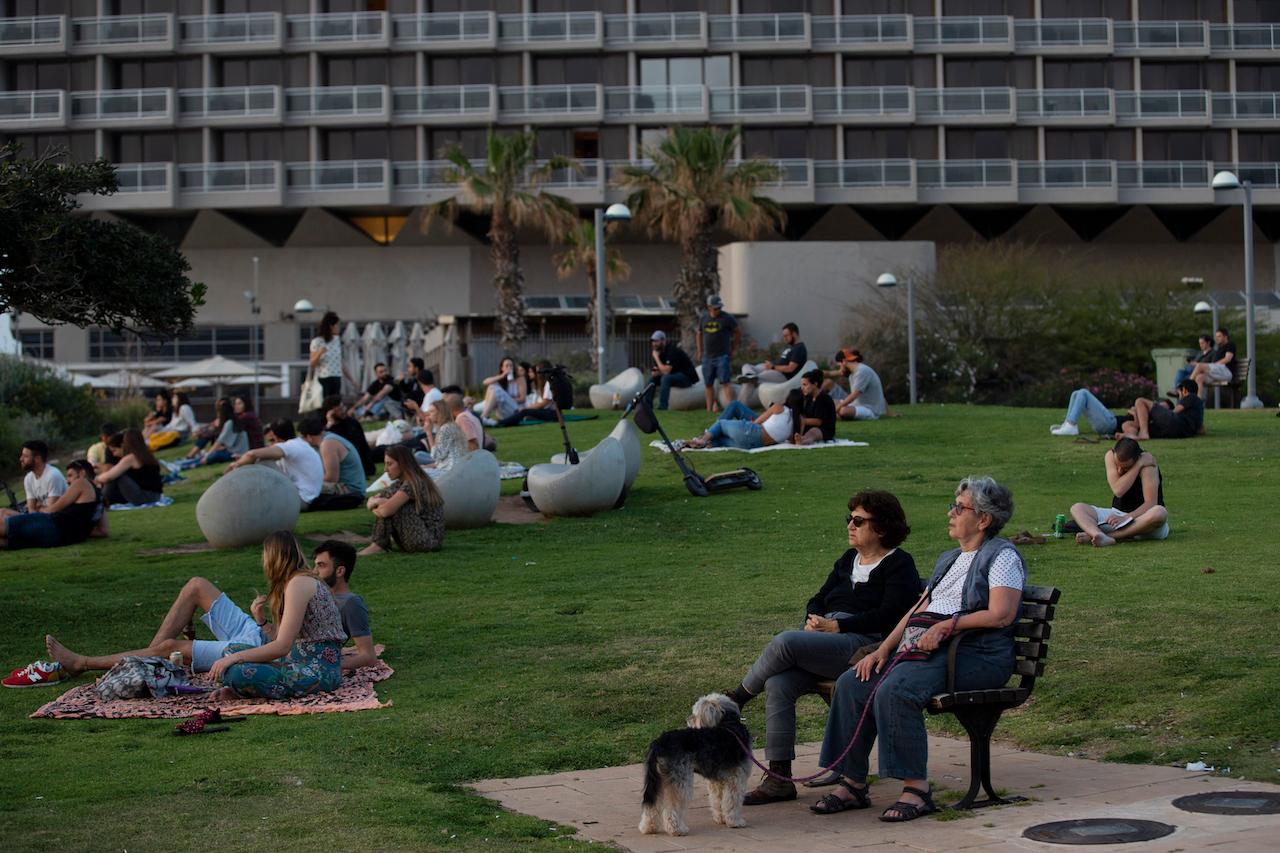 People without face masks watch the sunset, in Tel Aviv, Israel, April 18. Photo: AP