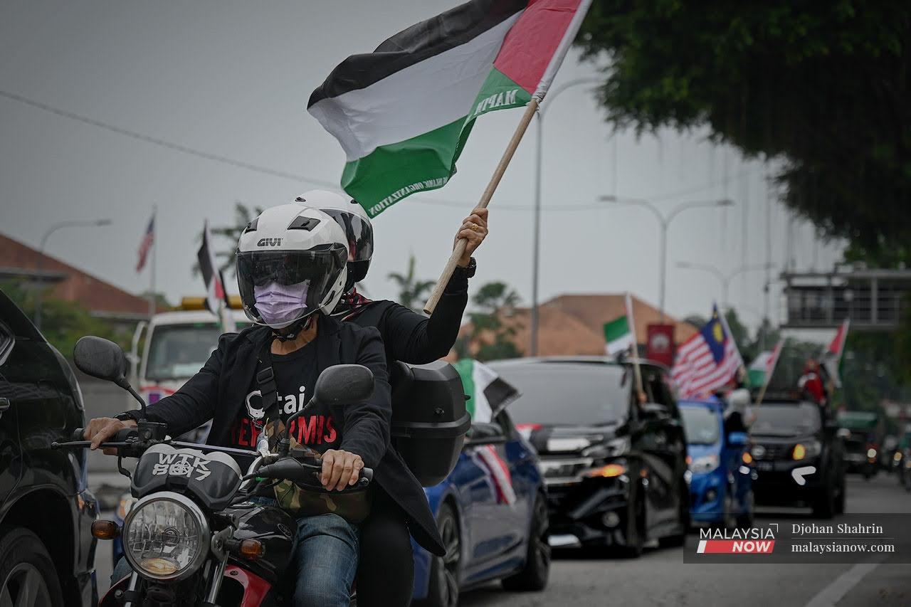 People wave Palestinian and Malaysian flags outside the US embassy in Jalan Tun Razak, Kuala Lumpur, on May 21, after a ceasefire was declared between Israel and Hamas.