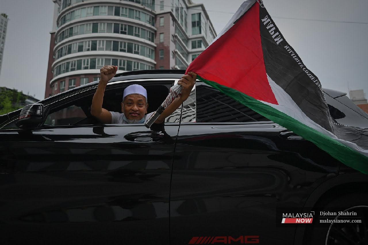 Seorang lelaki mengibarkan bendera Palestin ketika melalui Jalan Tun Razak.Gencatan senjata antara Israel dan gerakan Hamas diumumkan selepas 11 hari pertempuran hingga mengakibatkan lebih 200 rakyat Palestin terkorban.