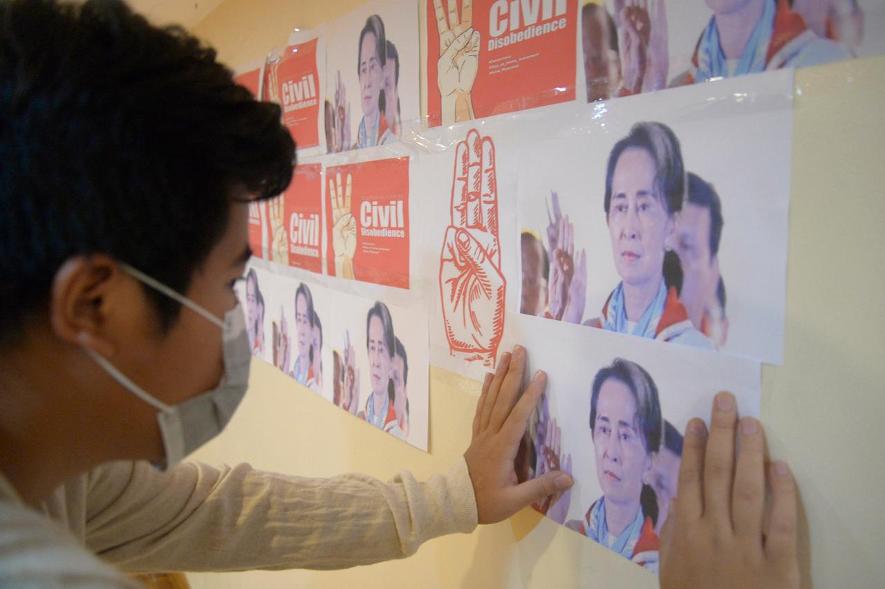 An anti-coup protester looks at images of ousted Myanmar leader Aung San Suu Kyi during a protest against the military coup in Yangon, Myanmar, April 26. Photo: AP