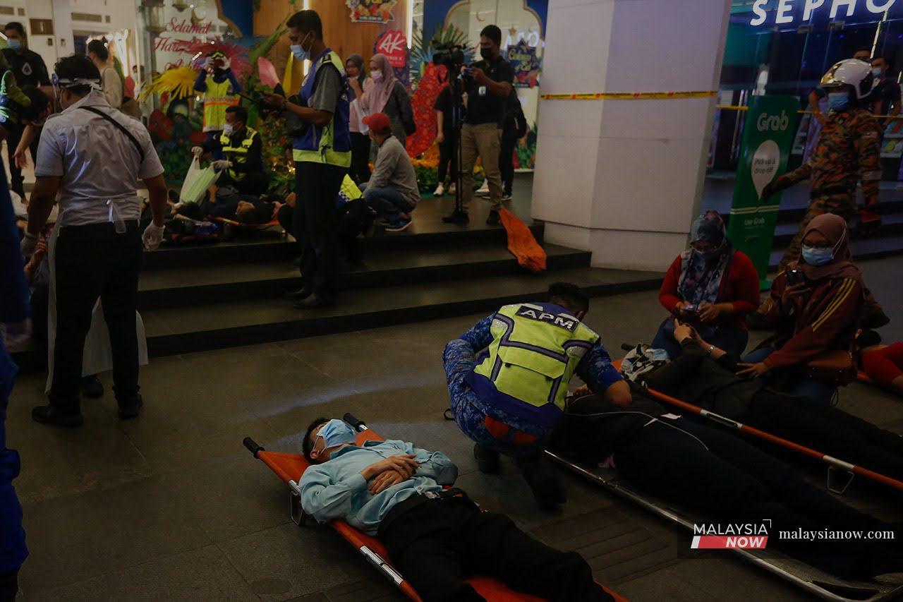 Passengers lie on stretchers on the ground after being helped out of the LRT train by personnel from the fire and rescue department after the collision last night.