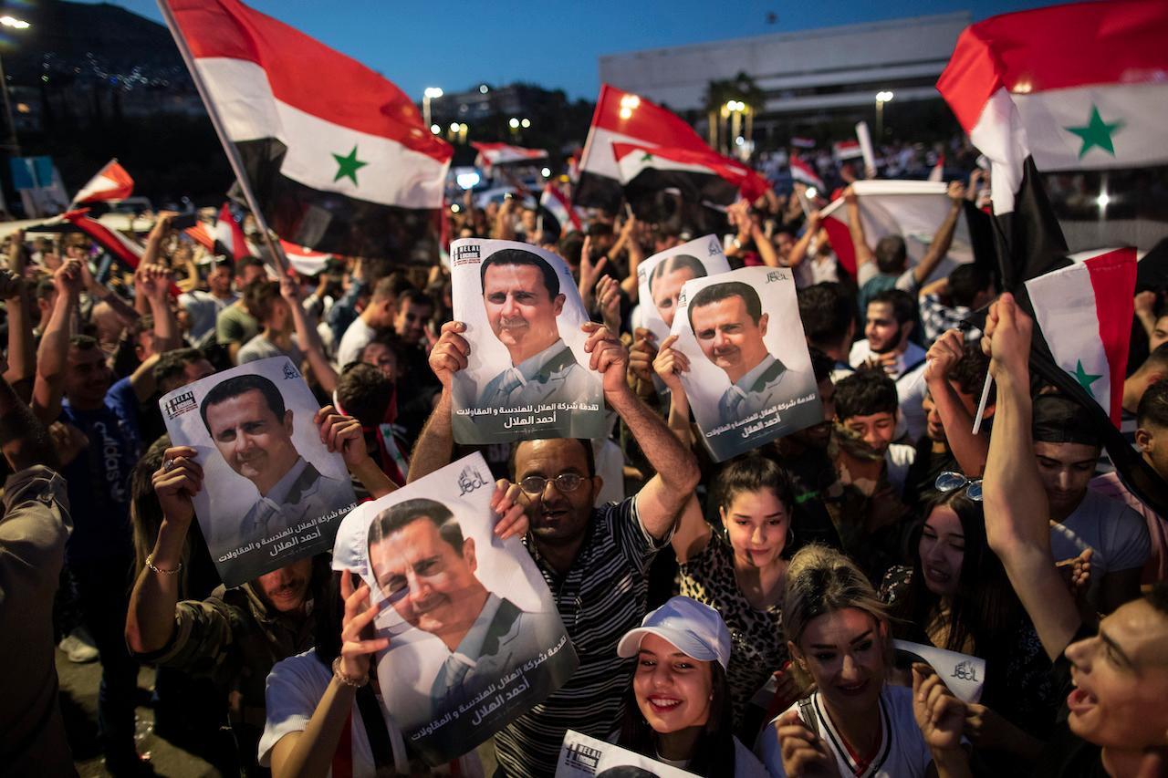 Supporters of Syrian President Bashar al-Assad hold up national flags and pictures of him as they celebrate at Omayyad Square, in Damascus, Syria, May 27. Photo: AP