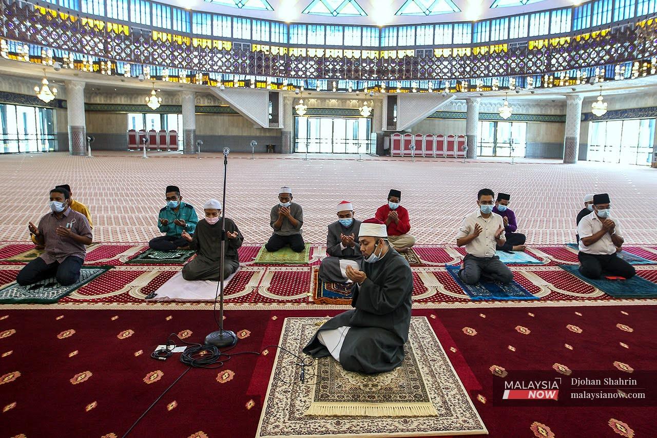 Jemaah solat Jumaat mengaminkan doa yang dibaca oleh Imam Muhammad Afif Jamal selepas menunaikan Solat Jumaat di Masjid Negara. Bilangan jemaah di masjid berkapasiti 1,000 orang kini dihadkan 50 orang sahaja.