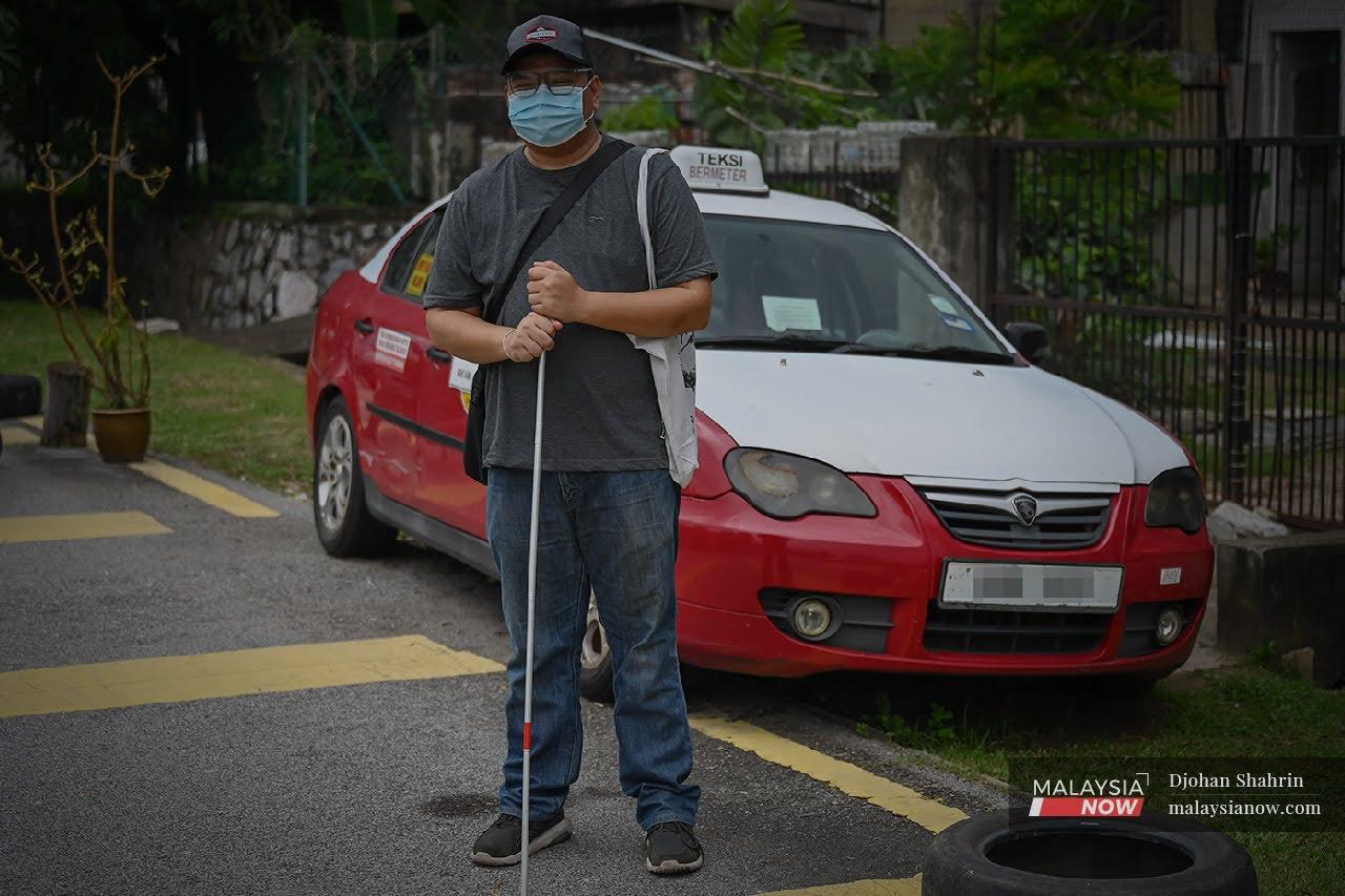Mohd Kamil Affendy Hashim,39, berdiri dihadapan teksinya, kini beliau terpaksa meninggal kerjaya pemandu teksi selepas mengalami penyakit keradangan mata di kedua-dua belah di Taman Bunga Raya, Setapak.