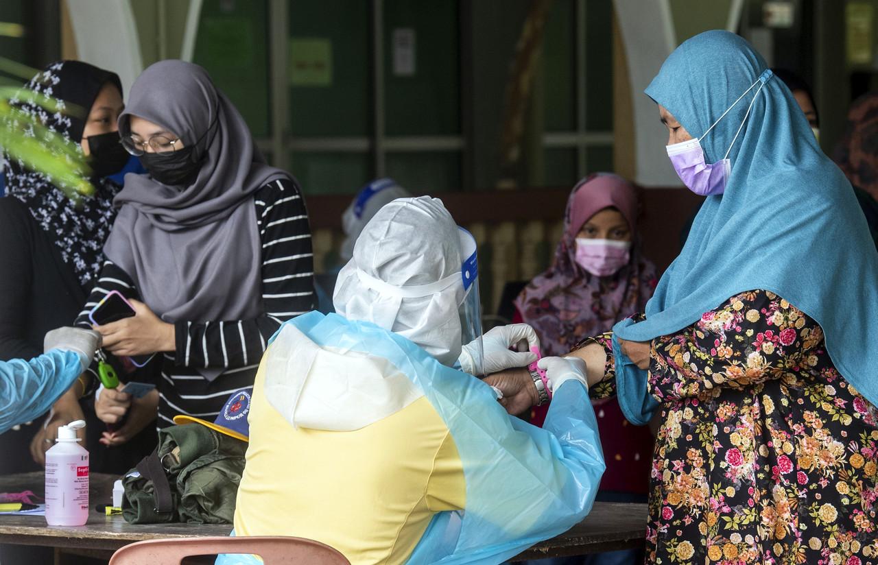 Petugas Kementerian Kesihatan Malaysia (KKM) memakaikan gelang tangan berwarna merah jambu kepada penduduk Kampung Pauh Lima pada 19 Mei, 2021. Gambar: Bernama