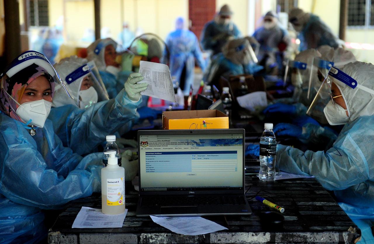 Health workers take down the details of people who have come to be screened for Covid-19 at Sabak Bernam in Selangor. Photo: Bernama