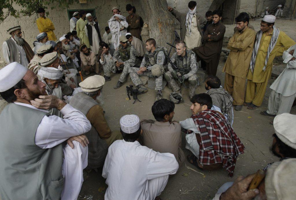 Members of the US military meet with villagers in Qatar Kala in the Pech Valley of Afghanistan's Kunar province with a local interpreter (centre left with hat). Former interpreters are becoming increasingly public about what they fear will happen should the Taliban return to power. Photo: AP