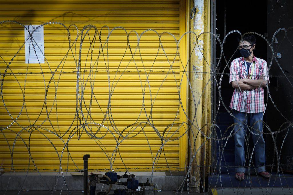 A men wearing a face mask stands behind barbed wire in a locked down area in Kuala Lumpur, May 15, 2020. A recent study shows that young people are among those most at risk of mental health problems during the pandemic. Photo: AP