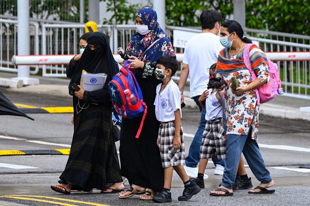 Children walk home with their guardians after school in Singapore on May 17, ahead of the government's move to shut all schools until the end of the term due to a spike in Covid-19 cases in the city-state. Photo: AFP
