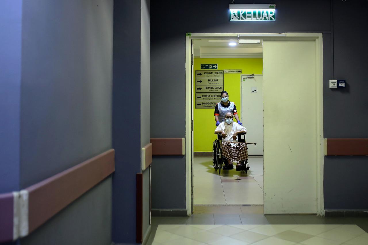 A health worker in Seremban pushes a senior citizen in a wheelchair at a vaccination centre at the KPJ Seremban specialist hospital. Photo: Bernama