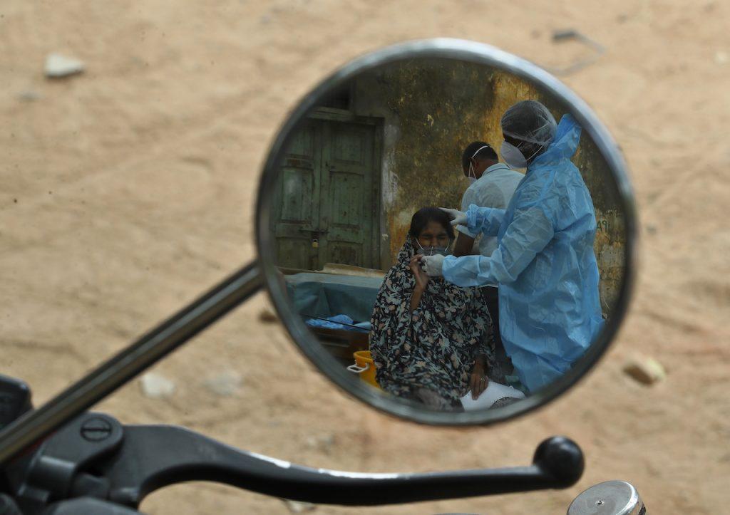 A health worker reflected in the mirror of a motorcycle takes a nasal swab sample from a woman to test for Covid-19, in Hyderabad, India, May 7. Under a new system announced by the World Health Organization, the so-called Indian variants of Covid-19 will now be known as Delta and Kappa. Photo: AP