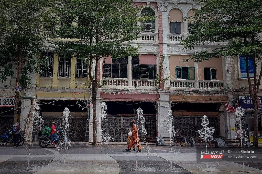 Pedestrians walk past a row of closed shophouses at Medan Pasar in Lebuh Ampang, Kuala Lumpur. The Malaysian Employers Federation says the current lockdown will make it difficult for employers to stay afloat without adequate support from the government.