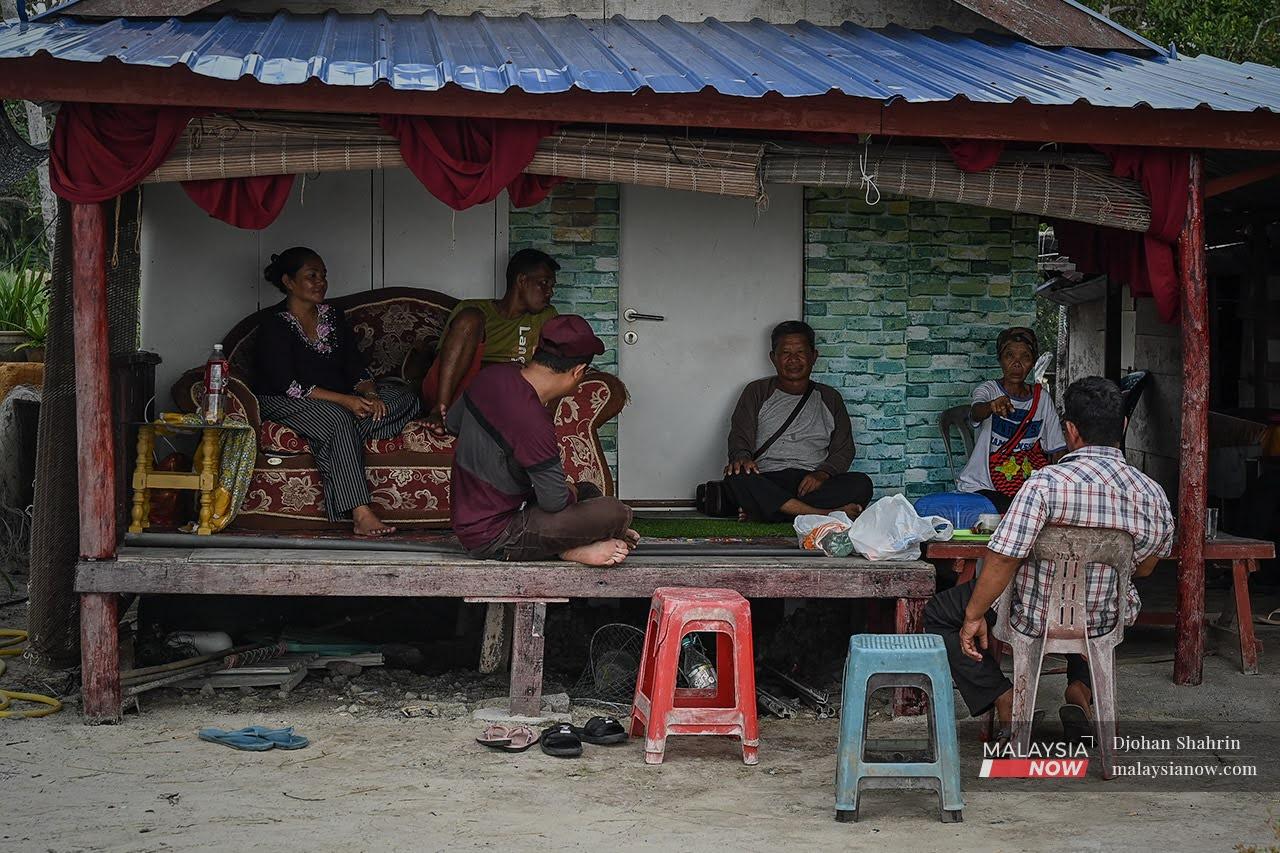 Orang Asli from the Mah Meri community sit outside a house in their settlement in Bagan Lalang, Selangor.