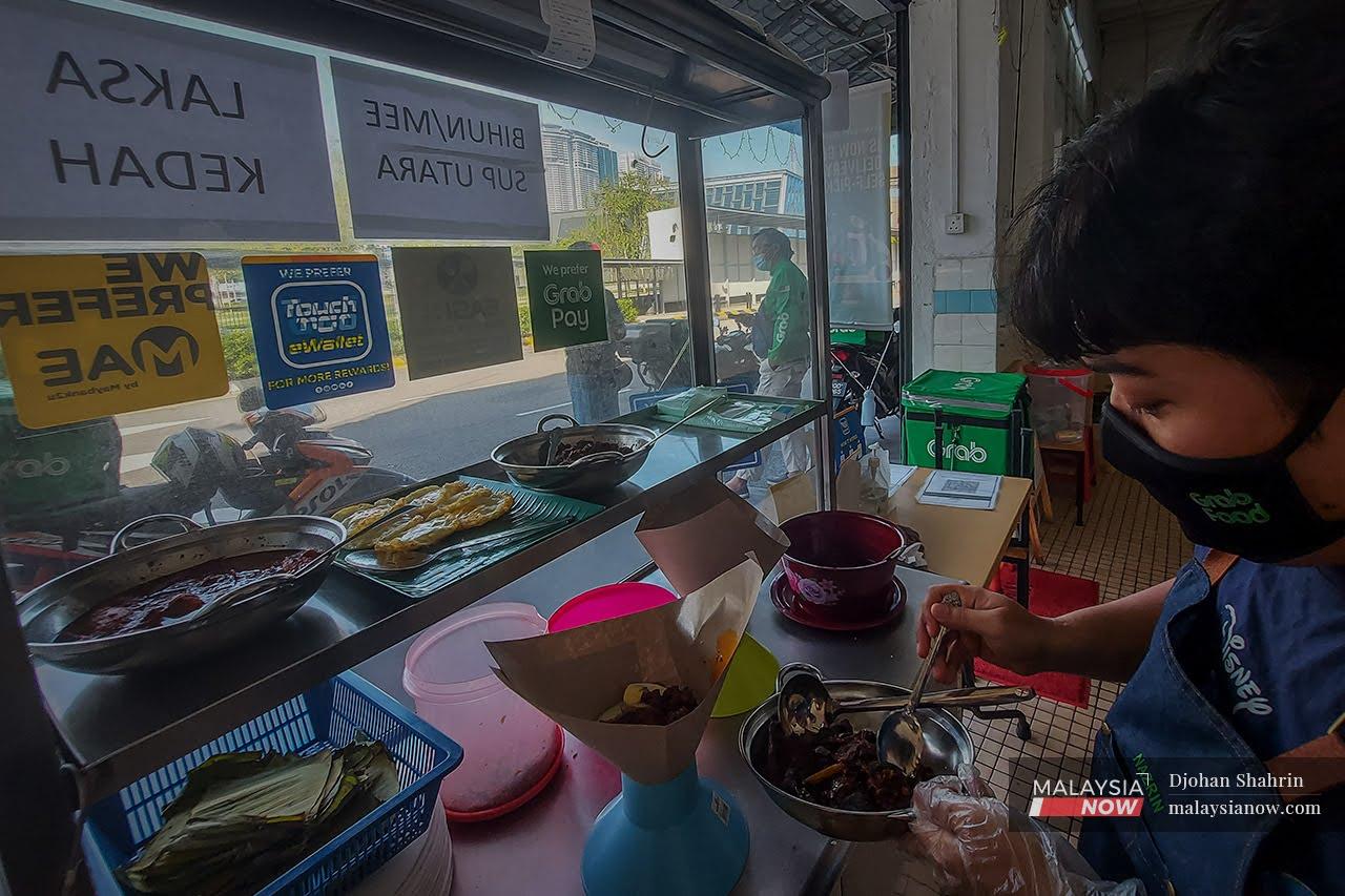 Peniaga kecil, Nazrin Idham Razali, 31, membungkus nasi lemak yang dipesan dari aplikasi Grabfood di Jalan Sultan, Kuala Lumpur.