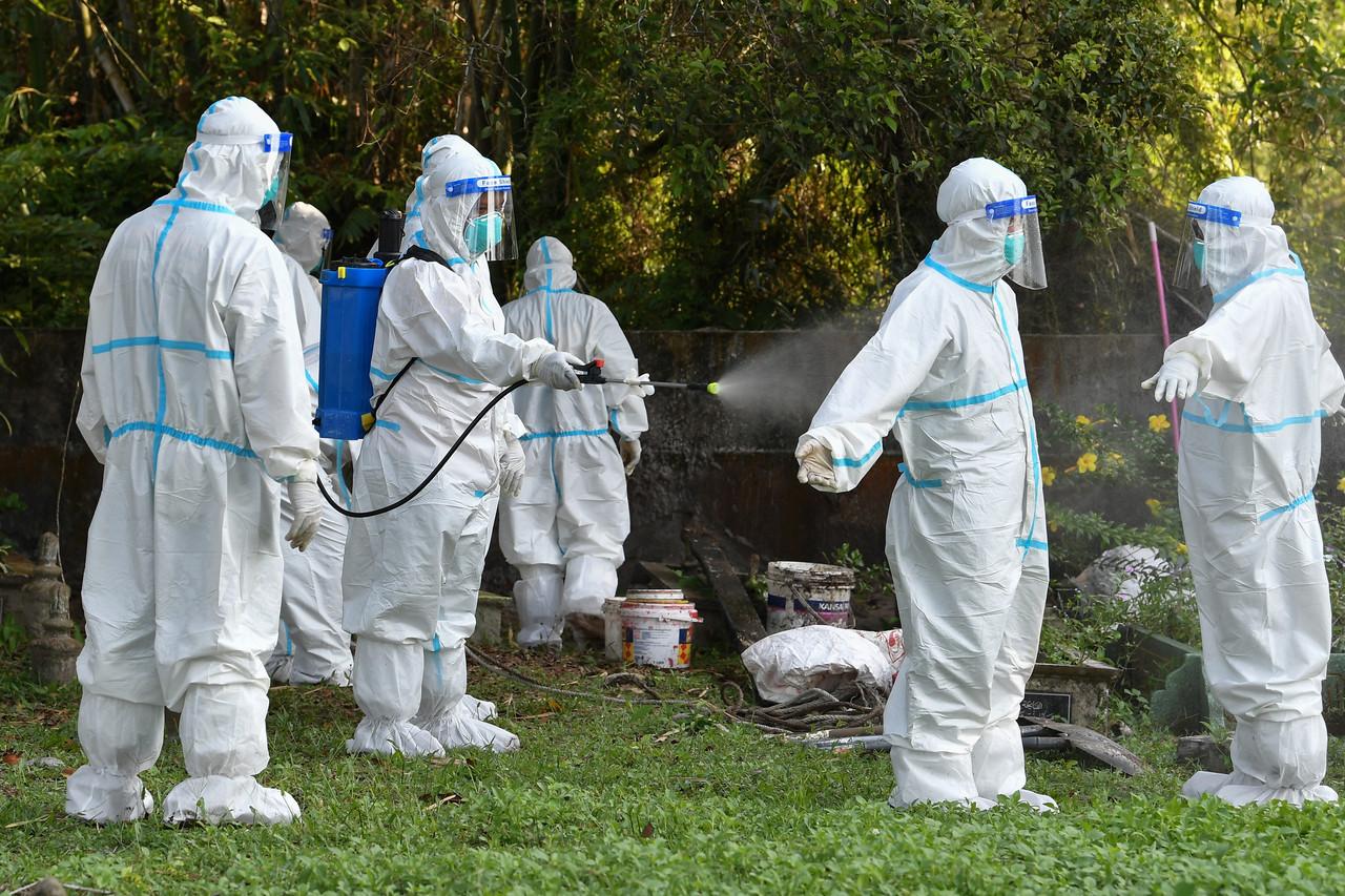 Personnel from the Terengganu fire and rescue department are sprayed down with sanitiser after the burial of a Covid-19 victim at the Kampung Kolam Kuala Ibai Islamic Cemetery in Kuala Terengganu. Photo: Bernama
