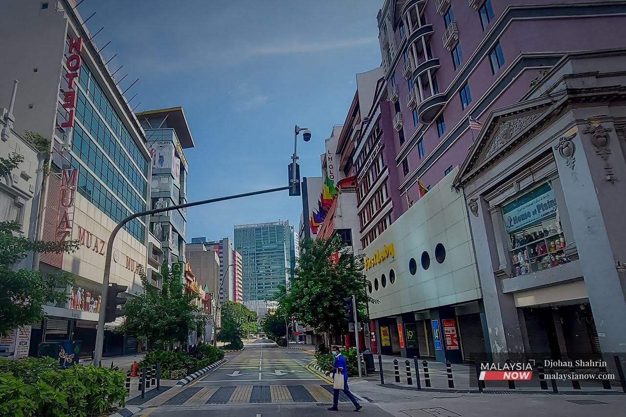 A pedestrian crosses a deserted road lined with closed shops at Jalan Tuanku Abdul Rahman in Kuala Lumpur during the total lockdown imposed to curb the spread of Covid-19.