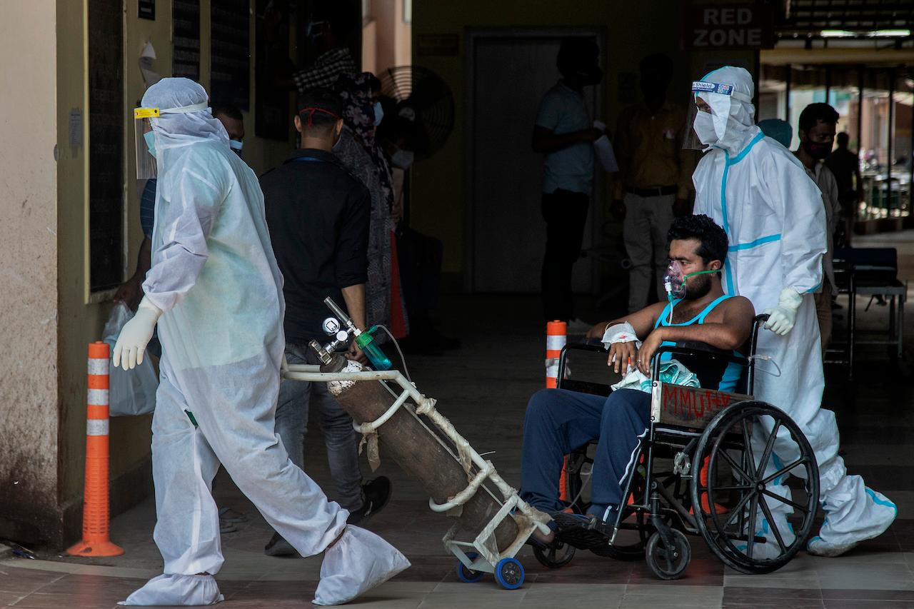 Health workers in protective suits shift a Covid-19 patient at a government hospital in Gauhati, India, May 24. Photo: AP