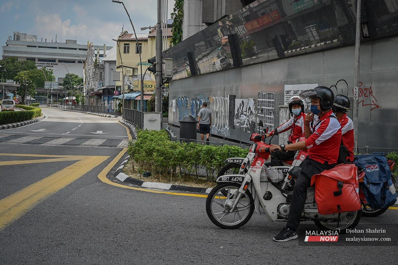 Tiga pekerja pos berhenti di persimpangan untuk kembali ke Pejabat Pos Besar di Jalan Tun Sambathan pada hari pertama perintah kawalan pergerakan 3.0. Kuala Lumpur lengang dari aktiviti dan kunjungan orang ramai.