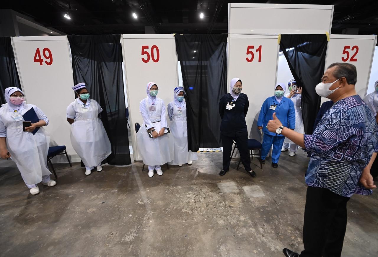 Prime Minister Muhyiddin Yassin speaks to frontline workers during a visit to the Mitec vaccination centre in Kuala Lumpur yesterday. Photo: Bernama