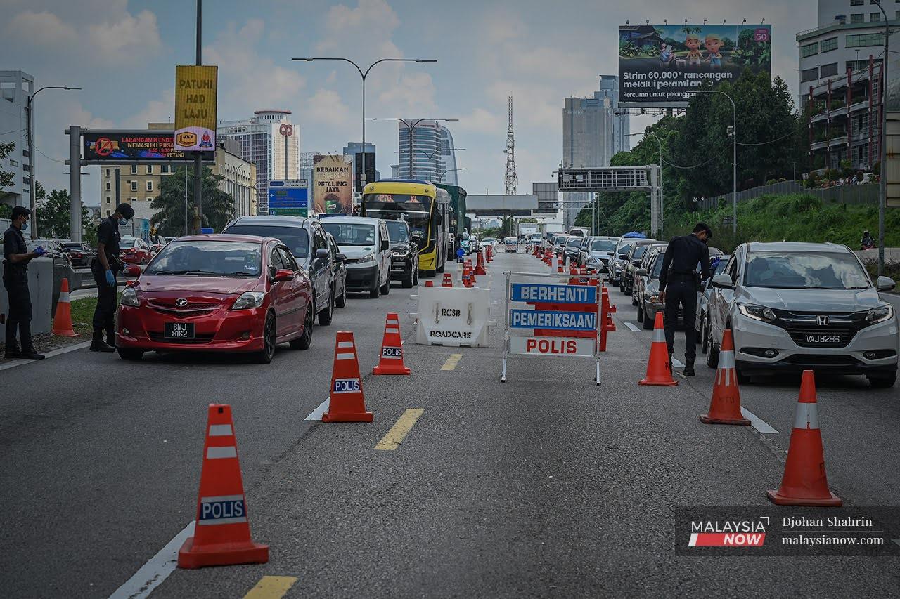 Police check vehicles at a roadblock along Selangor-Kuala Lumpur border at the Federal Highway during the movement control order.