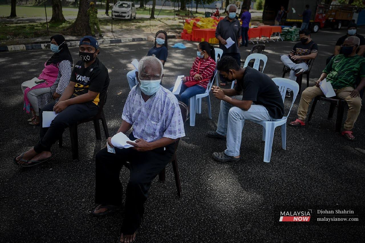Penduduk Orang Asli Temuan duduk menunggu giliran sebelum melakukan ujian saringan RTK-antigen secara percuma oleh pasukan kesihatan Klinik Selcare di Desa Temuan, Bukit Lanjan, Selangor.