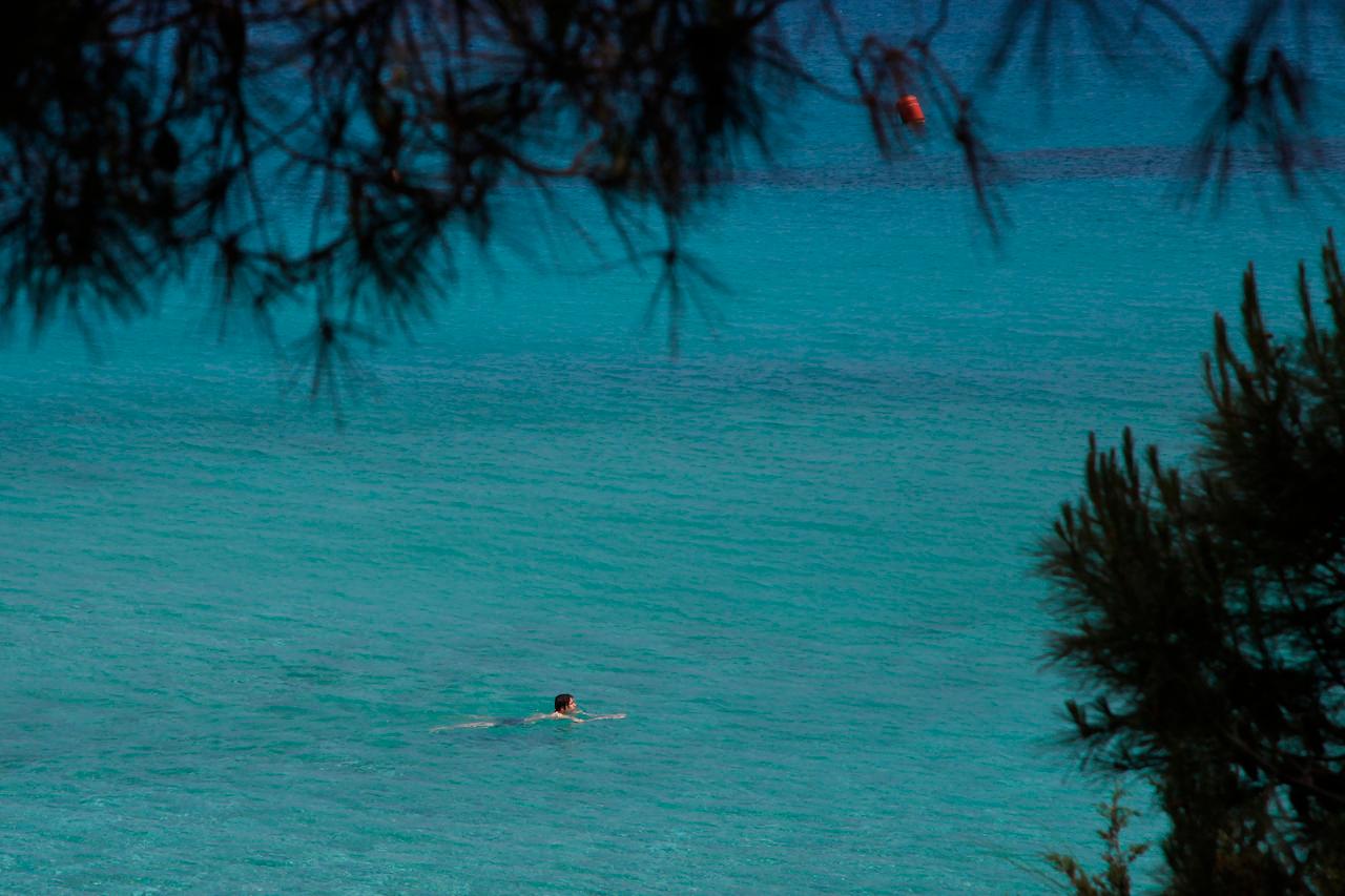 A lone person swims through the clear waters off the Konnos beach in Ayia Napa, Cyprus. An inquiry report says over half of the passports issued under Cyprus' passports-for-cash scheme were granted illegally. Photo: AP