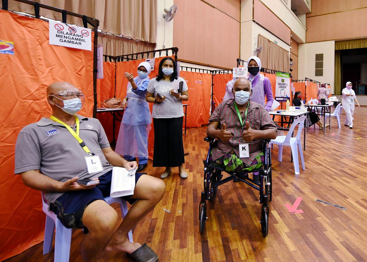 A wheelchair-bound man gives the thumbs up sign after receiving his first dose of Covid-19 vaccine at the vaccination centre in Wisma Belia, Kuantan. Photo: Bernama